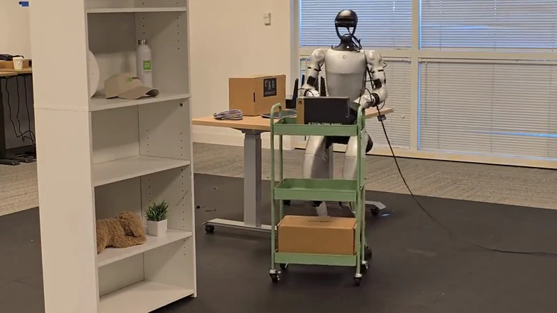 Official GR00T N1.6 policy rollout: a humanoid robot moves a cart and reaches toward shelves.